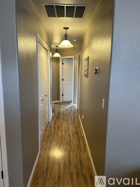 A long hallway with a light on the ceiling and a door at the end.