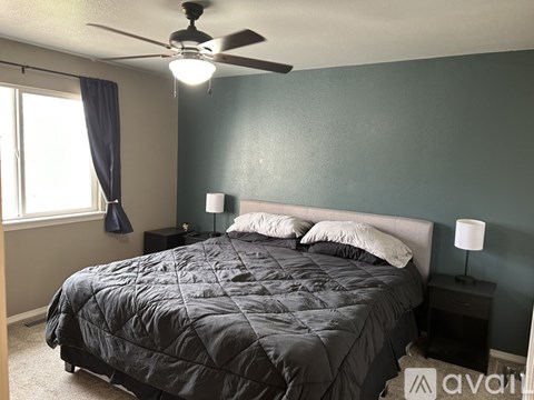 A bedroom with a bed, two lamps, and a ceiling fan.