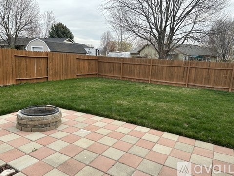 A backyard with a fire pit and a wooden fence.