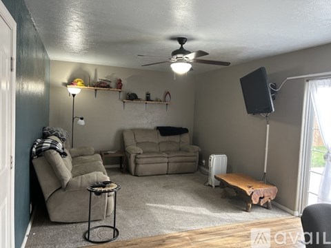 A living room with a couch, chair, and a fan.