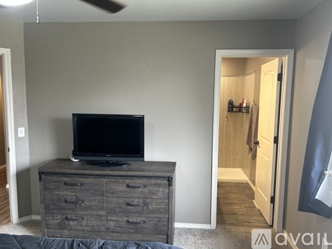 A black television sits on top of a wooden dresser.