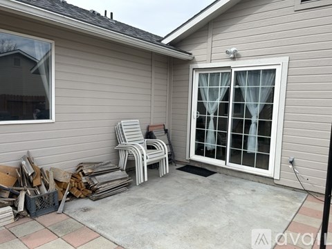 A patio with a white chair and a window with curtains.