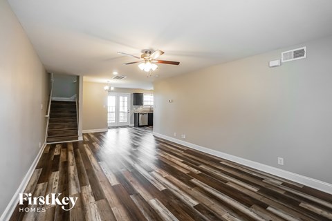 A spacious room with wooden flooring and a ceiling fan.