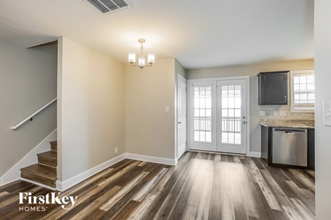 A kitchen area with a stainless steel dishwasher and a fridge with a microwave above it.