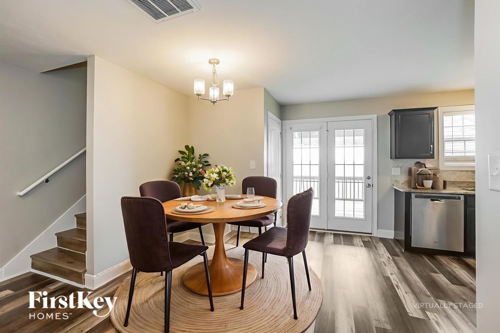 A dining room with a table set for four and a kitchen area in the background.