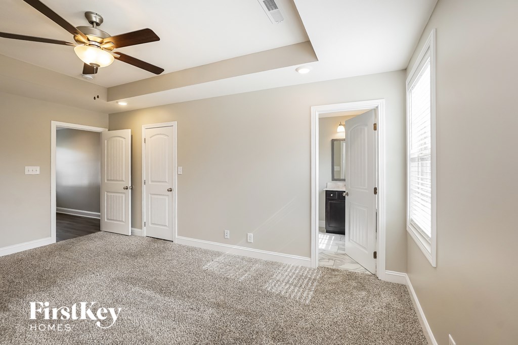 A spacious room with a ceiling fan and a carpeted floor.