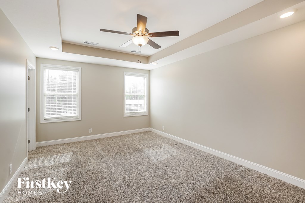 A room with a ceiling fan and two windows.