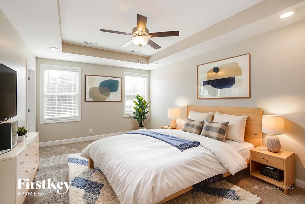 A bedroom with a bed, a ceiling fan, and a plant.