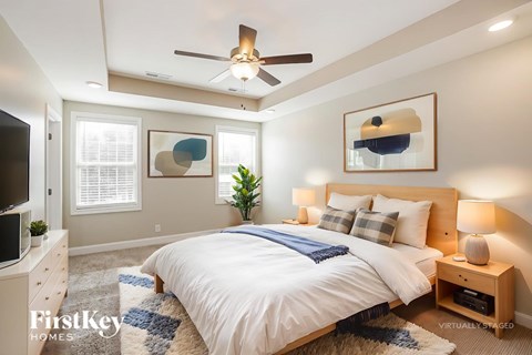 A bedroom with a bed, a ceiling fan, and a plant.
