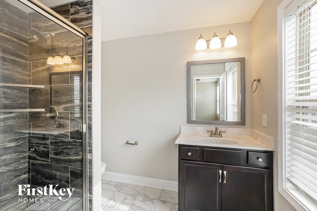 A bathroom with a marble shower and a white sink vanity.