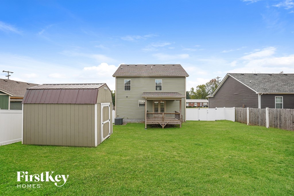 A backyard with a shed, a house and a fence.