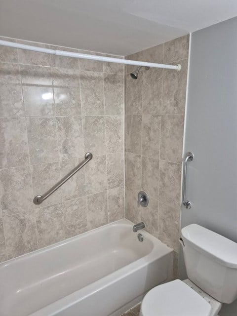 A white toilet sits next to a bathtub in a bathroom.