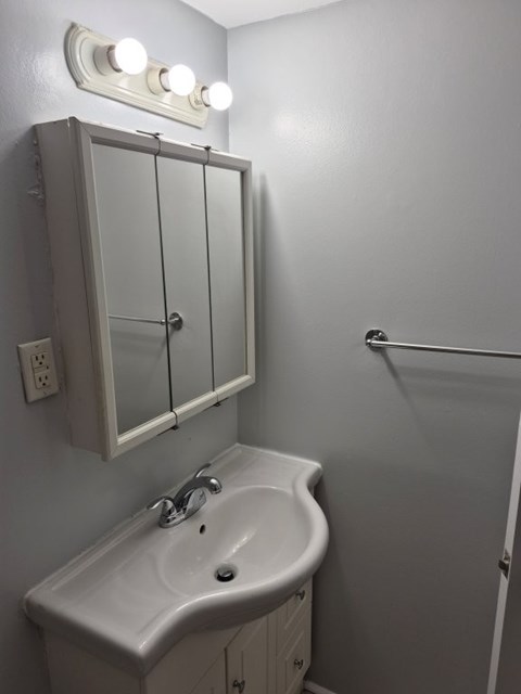 A white sink in a bathroom with a mirror above it.