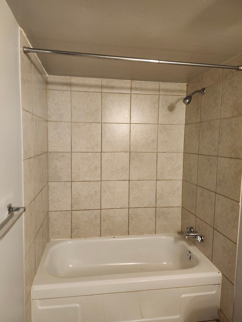 A white bathtub in a bathroom with tiled walls.