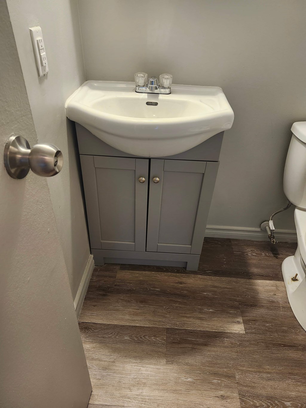 A white sink with a silver faucet and a silver door knob.