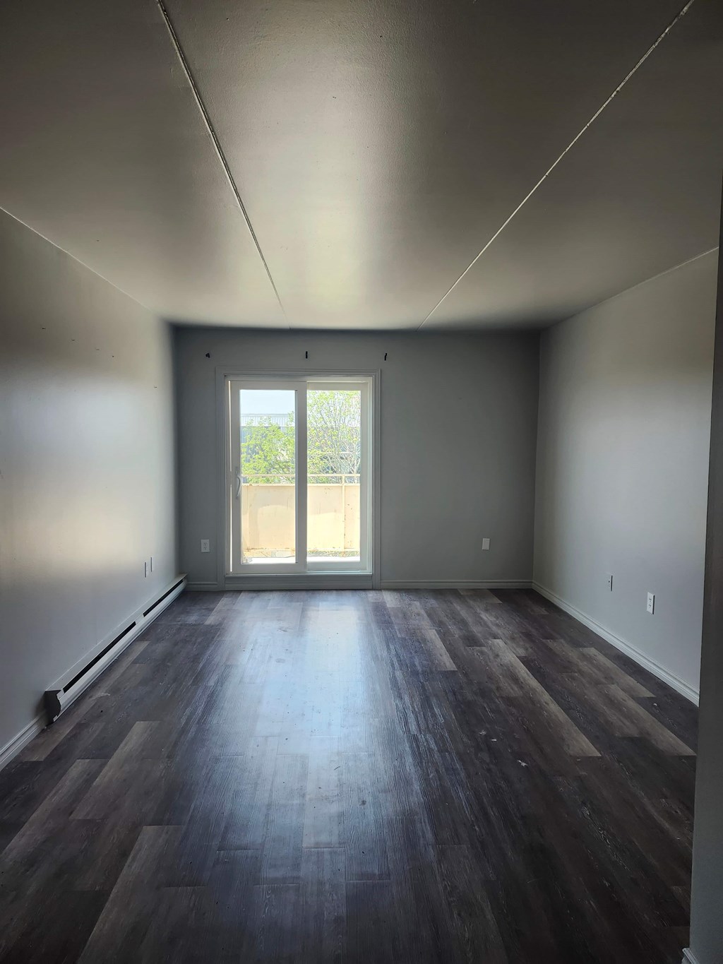 A room with a wooden floor and a sliding glass door.