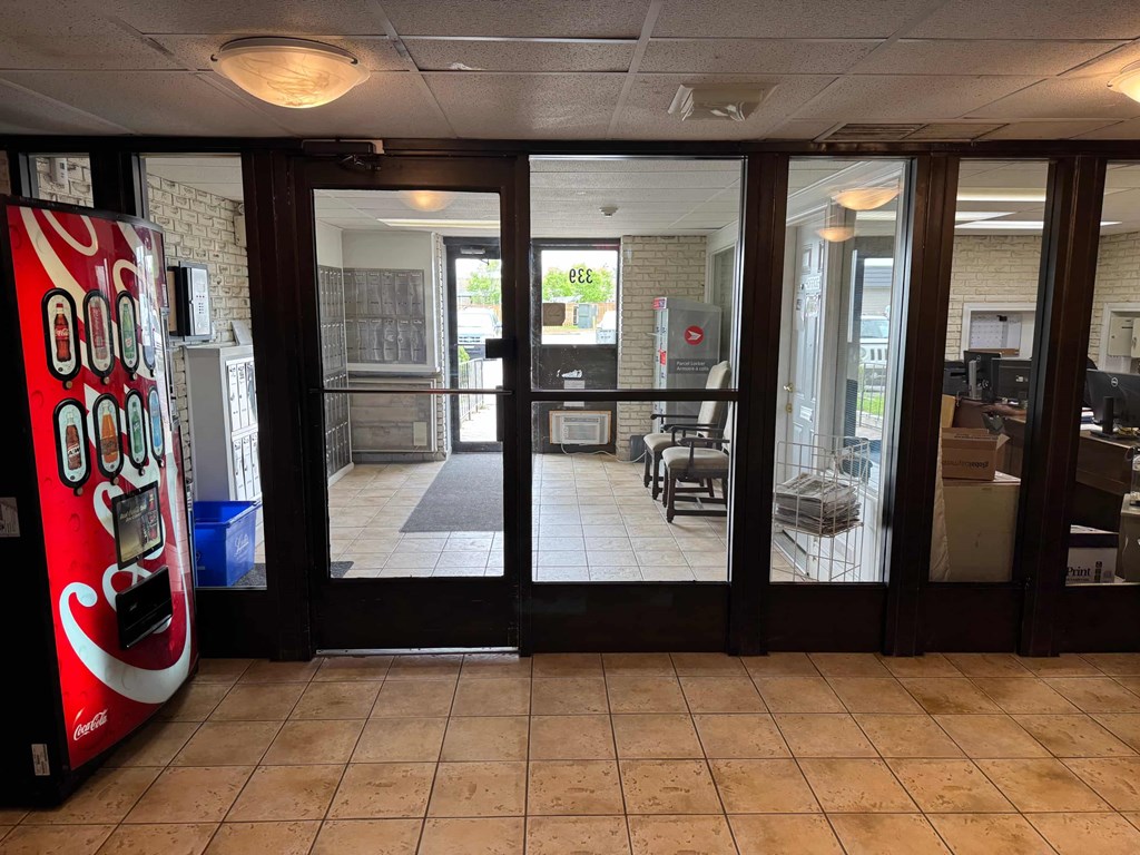 A Coca-Cola vending machine is in the foreground of a glass door entrance.