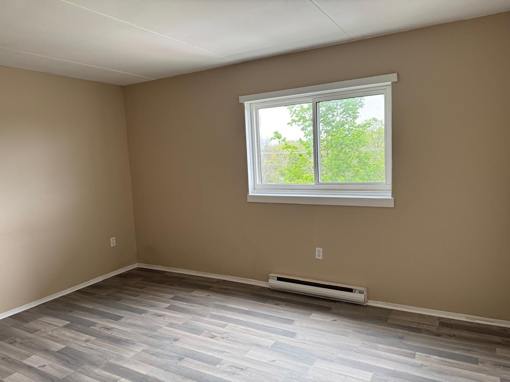 A room with a window and a heater on the floor.