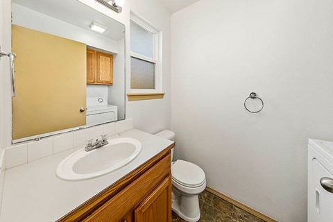 A bathroom with a toilet, sink, and a window.