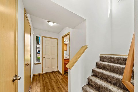 A hallway with a staircase and a white door.