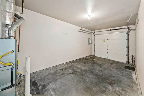A garage with a white door and a concrete floor.