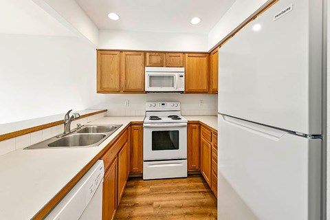 A kitchen with white appliances and wooden cabinets.