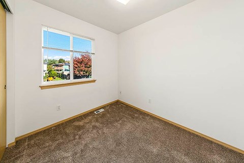 A room with a window showing a view of a building and trees.