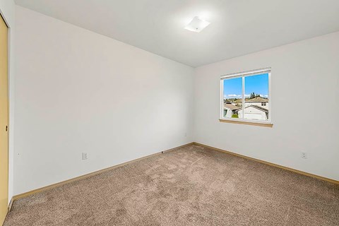 A room with a window showing a view of a house.