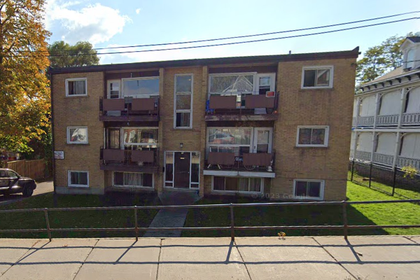 Apartment building with a black car parked in front.