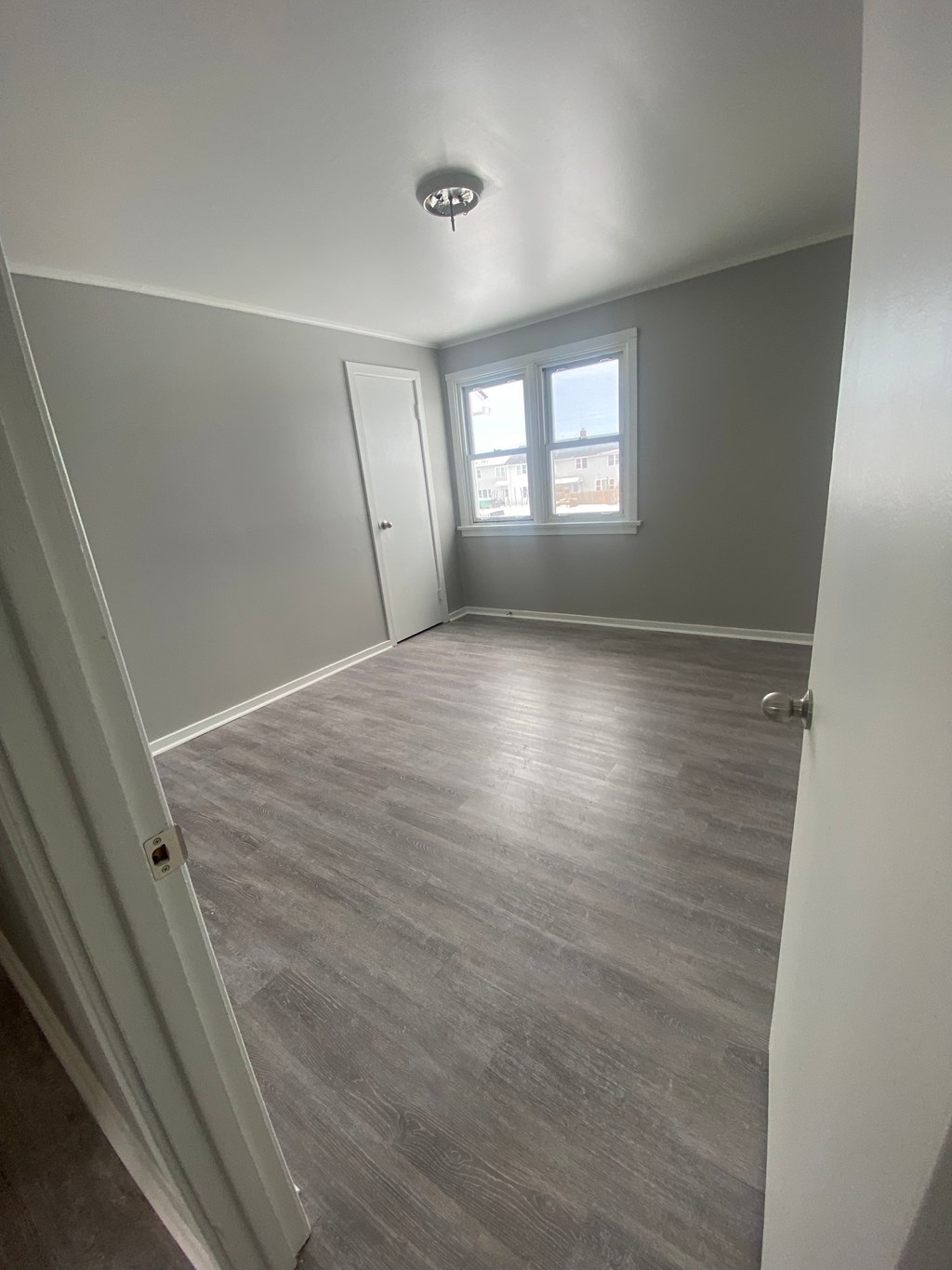 A room with a grey floor and a window letting in light.