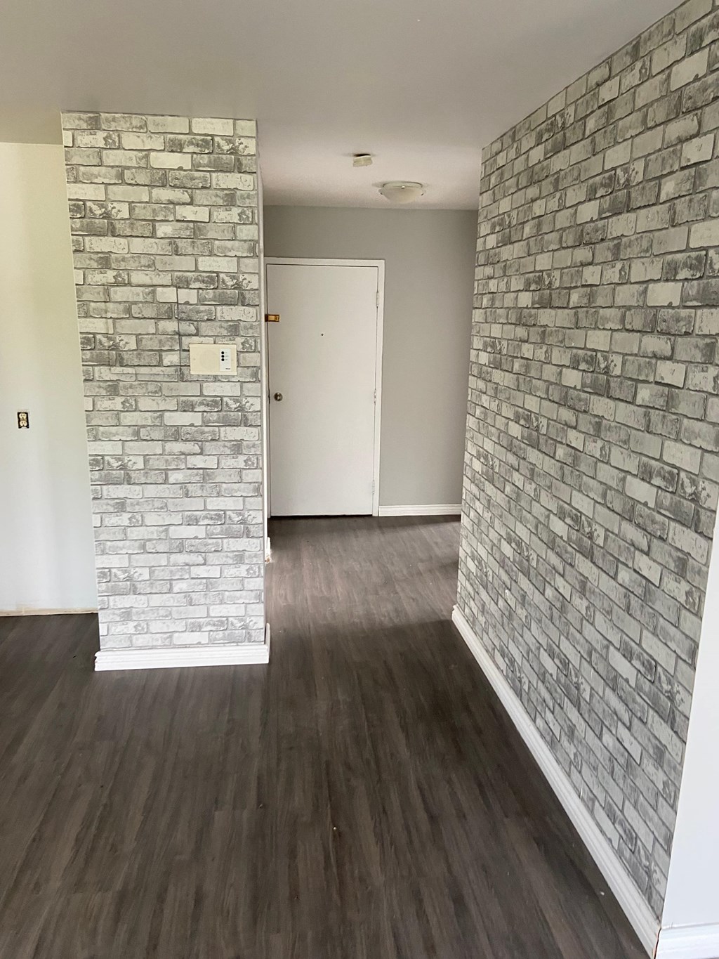 A room with a white door and a brick wall.