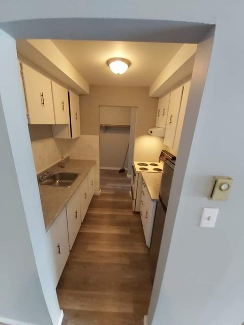 A kitchen with white cabinets and wooden floors.