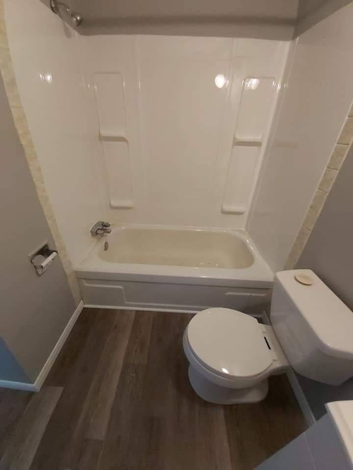 A white toilet sits next to a bathtub in a bathroom.