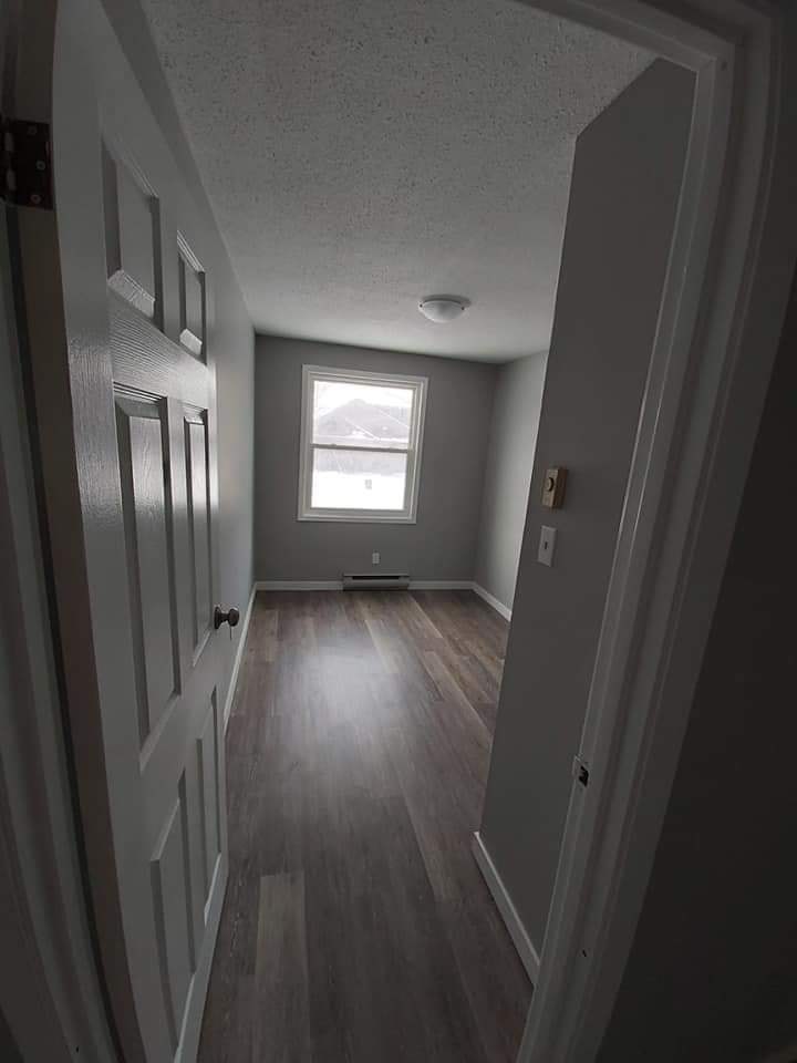 A hallway with wood floors and white walls.