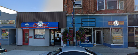 A car is parked in front of a building with a blue awning.
