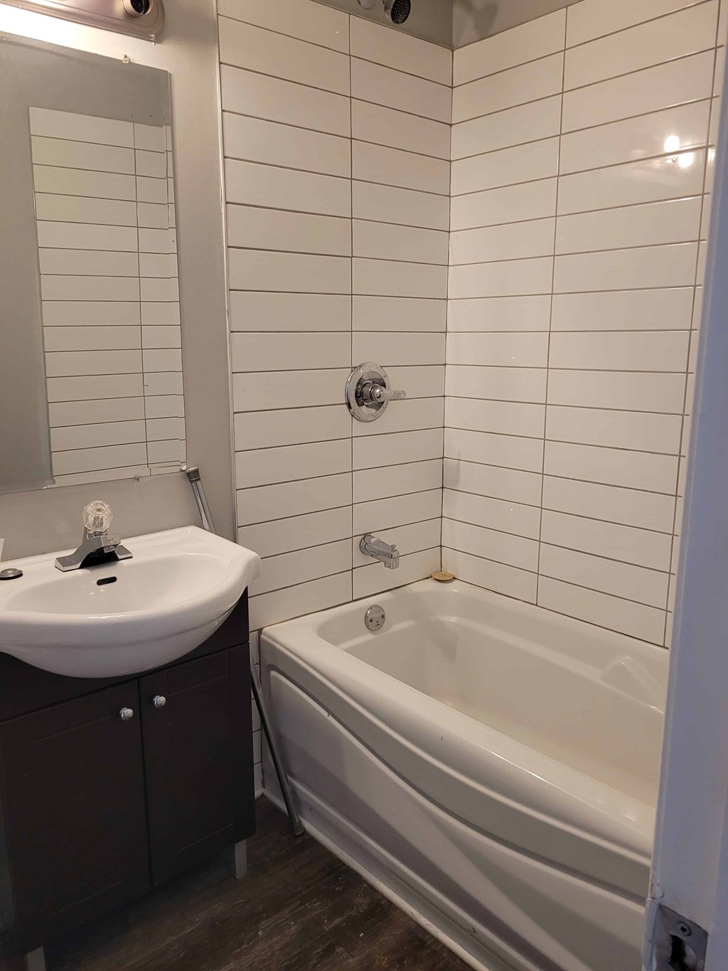 A white sink with a mirror above it and a white bathtub in a bathroom.
