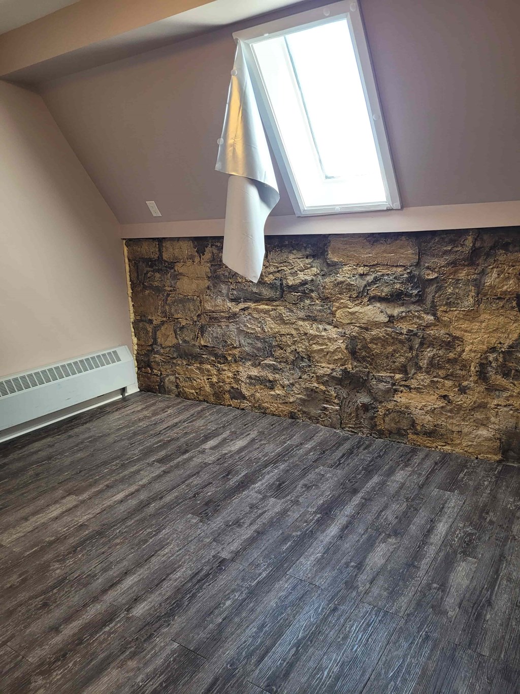 A room with a stone wall and wooden flooring.