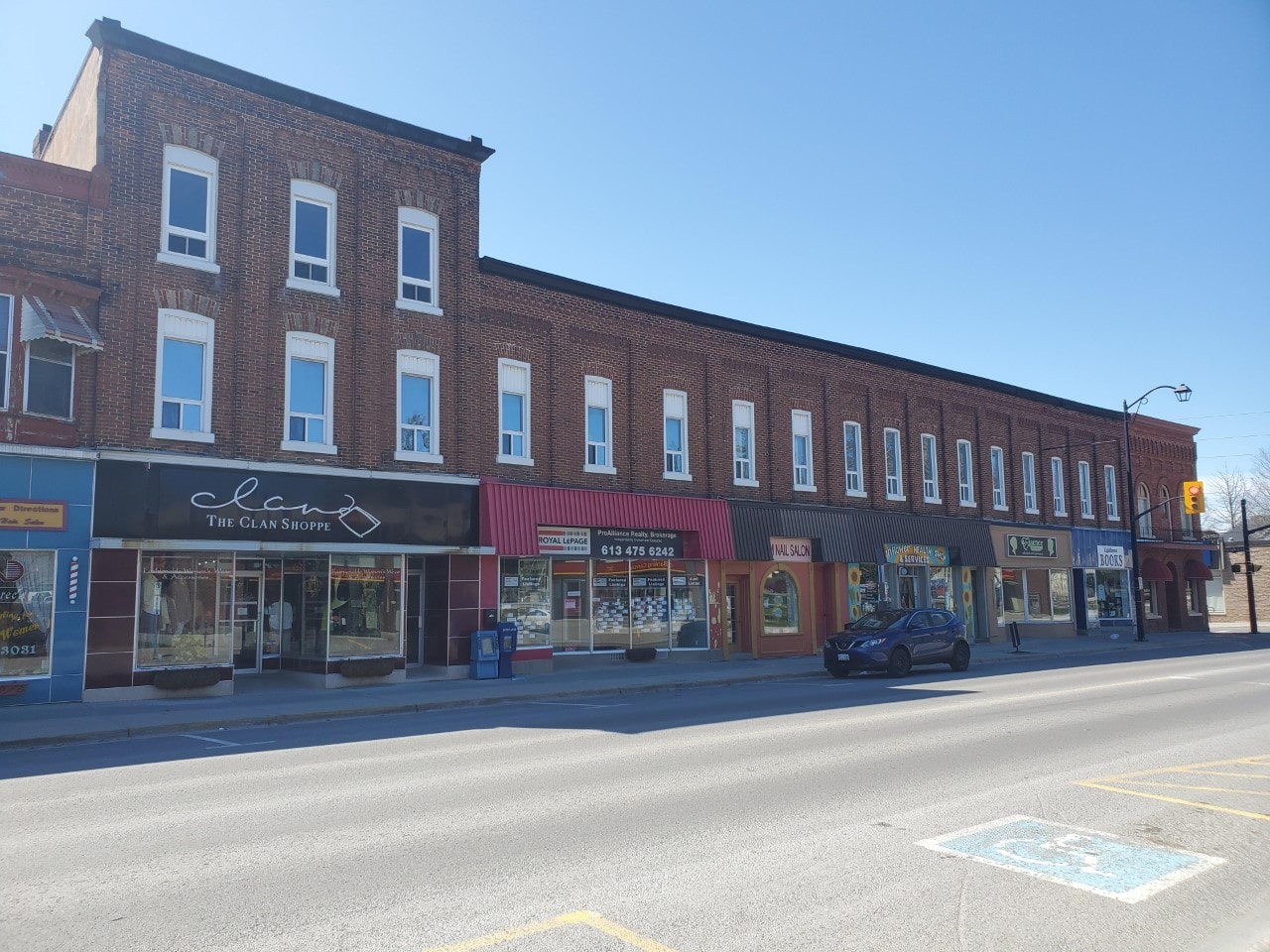 A street view of a row of shops with a blue car parked in front of the first shop.