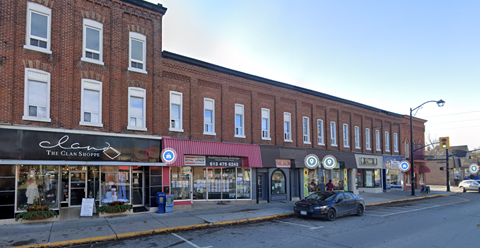 A street view of a row of shops with a car parked on the side of the road.