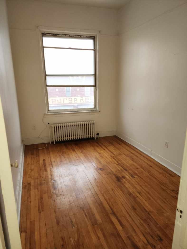 A room with a window and a radiator on the floor.