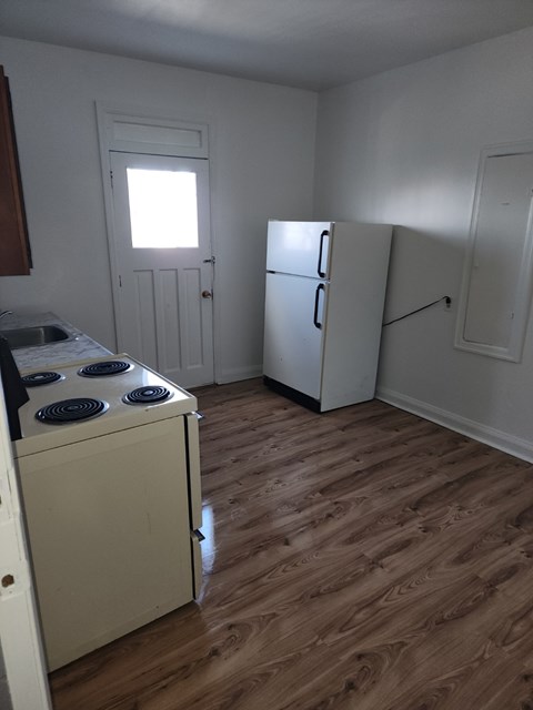 A kitchen with a stove, refrigerator, and cabinets.
