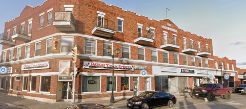 A red brick building with a black car parked in front.