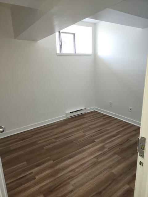 A room with a brown wooden floor and a window.