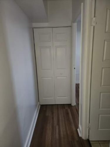A white door is in a hallway with a wooden floor.