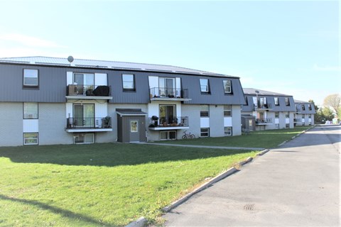 A row of townhouses with balconies and green lawns.