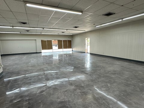 A spacious empty room with grey flooring and white walls.