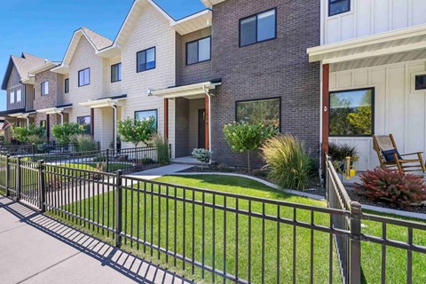 A row of houses with a black fence in front.