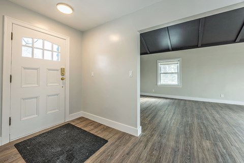 A room with a door, a window, and a rug on the floor.