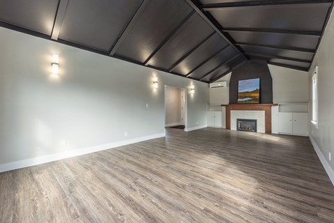 A spacious room with wood flooring and a fireplace.