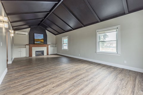 A spacious room with wood flooring and a fireplace.